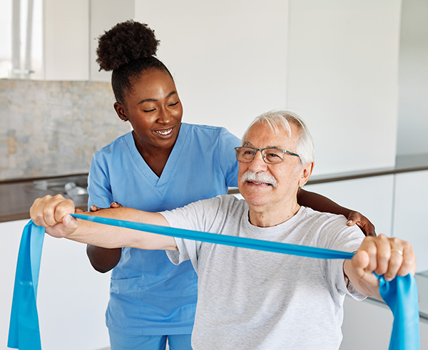 A carer helping an elderly man with physical therapy