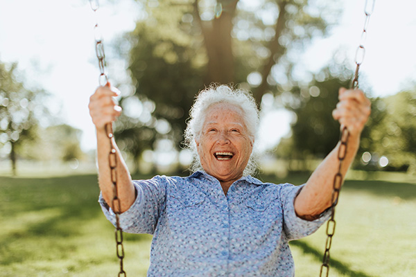 A woman on a swing smiling and having fun.