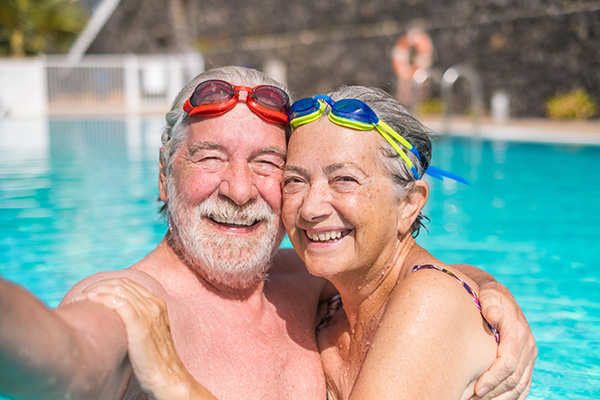 An elderly couple in a pool relaxing and smiling.