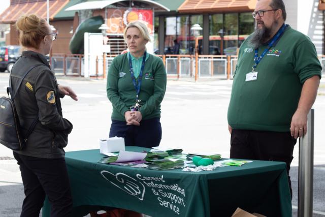 Three people stood around a table outside