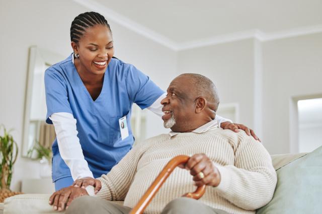 Carer helping and elderly man with a walking stick