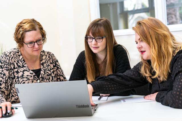 Three women around a computer