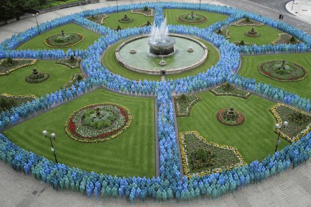 Hundreds of naked people painted blue stood around a water fountain